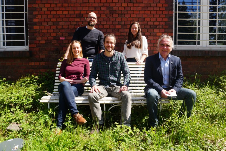 Teambild des Projekts SEVAS. Eine Frau und zwei Männer sitzen auf einer Prakbank, ein Mann und eine Frau stehen dahinter.